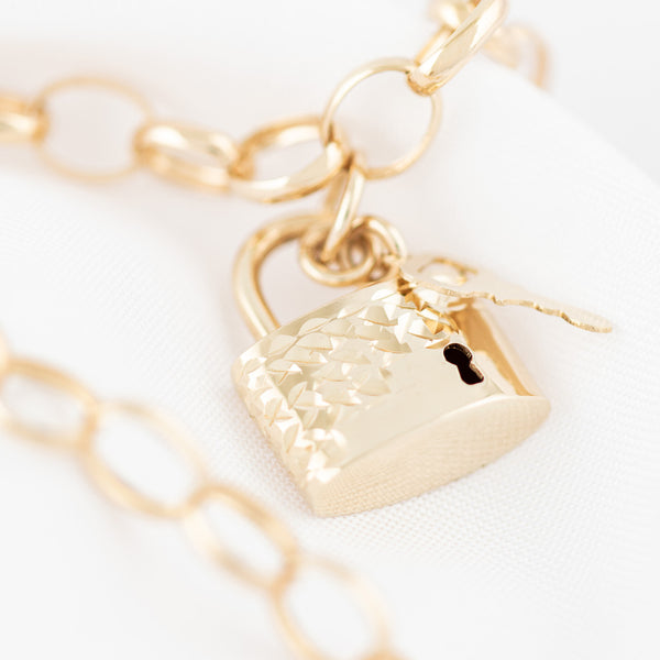 Pulsera eslabón cruzado con colgantes motivo candado y llave en oro amarillo 14 kilates.