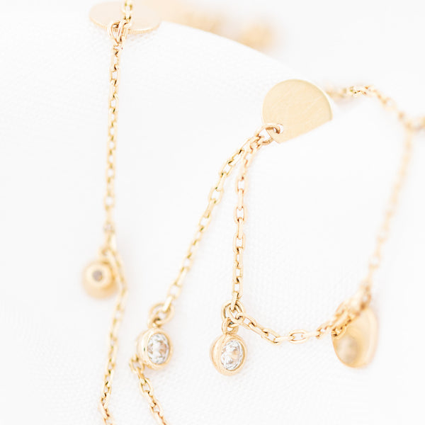 Pulsera eslabón cruzado con colgantes motivo círculos y circonias en oro amarillo 14 kilates.
