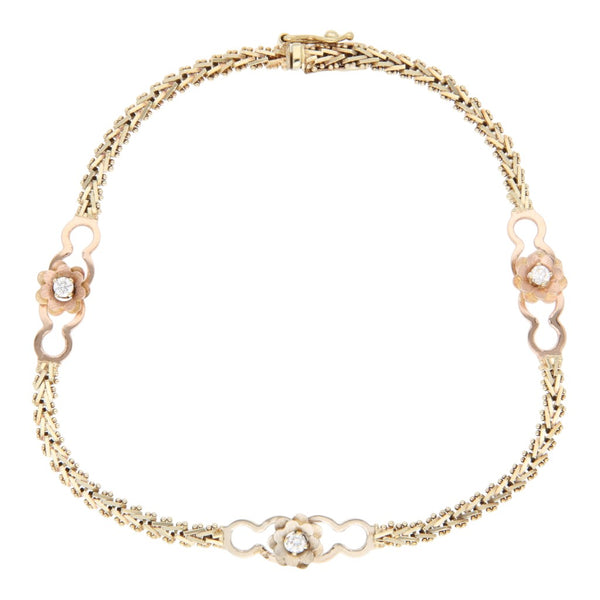 Pulsera eslabón combinado con aplicaciones motivo flor y circonias en oro tres tonos 14 kilates.