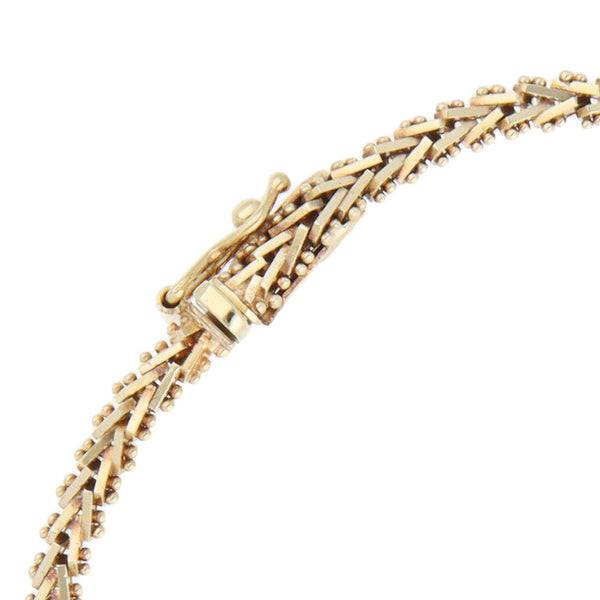 Pulsera eslabón combinado con aplicaciones motivo flor y circonias en oro tres tonos 14 kilates.