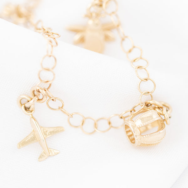 Pulsera eslabón cruzado con colgantes figuras diferentes en oro amarillo 14 kilates.