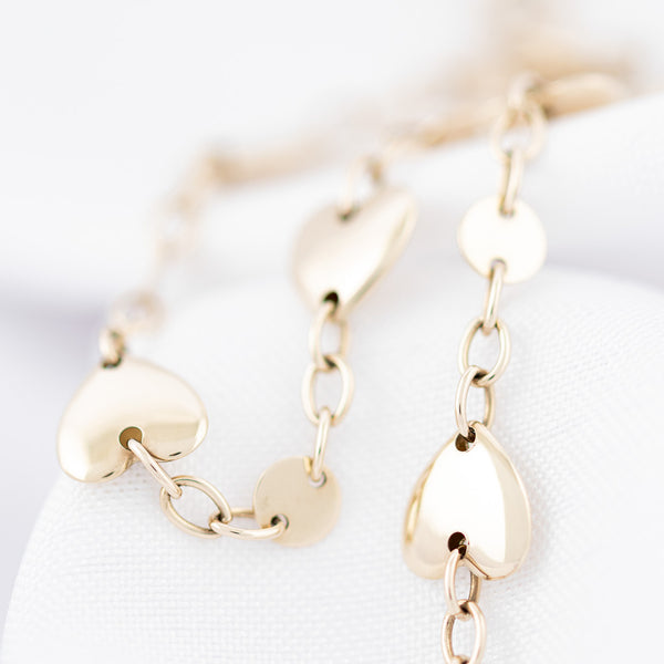 Pulsera eslabón cruzado con aplicaciones de corazón en oro amarillo 14 kilates.