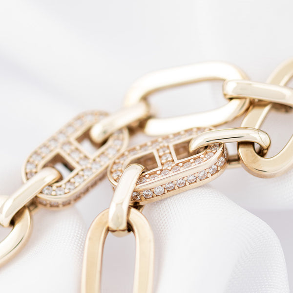 Pulsera eslabón cruzado con aplicaciones de circonias en oro amarillo 14 kilates.