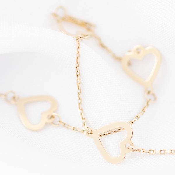 Pulsera eslabón cruzado con aplicaciones motivo corazón y sintético en oro amarillo 14 kilates.