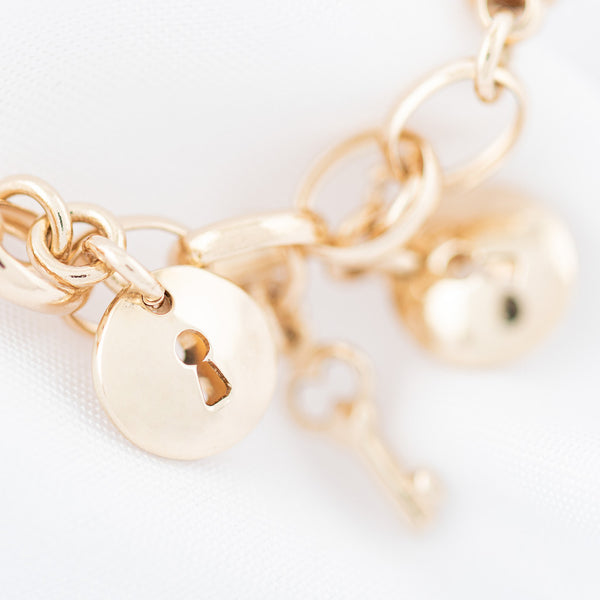 Pulsera eslabón combinado con colgantes motivo llave y cerradura en oro amarillo 14 kilates.