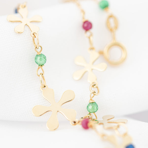 Pulsera eslabón combinado con aplicaciones motivo flor y sintéticos en oro amarillo 14 kilates.