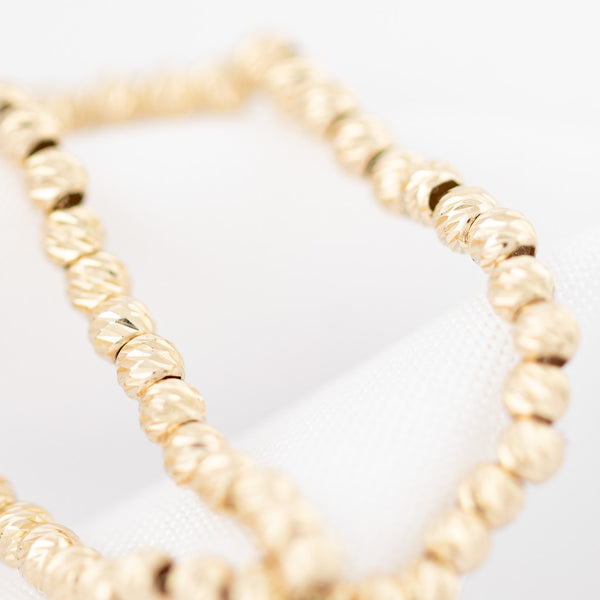 Pulsera eslabón cruzado con aplicaciones motivo esferas en oro amarillo 14 kilates.