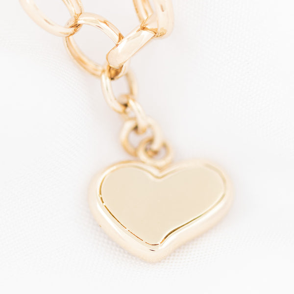 Pulsera eslabón cruzado con colgante motivo corazón en oro amarillo 14 kilates.