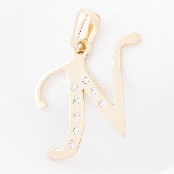 Dije diseño especial motivo letra N con circonias en oro amarillo 14 kilates.