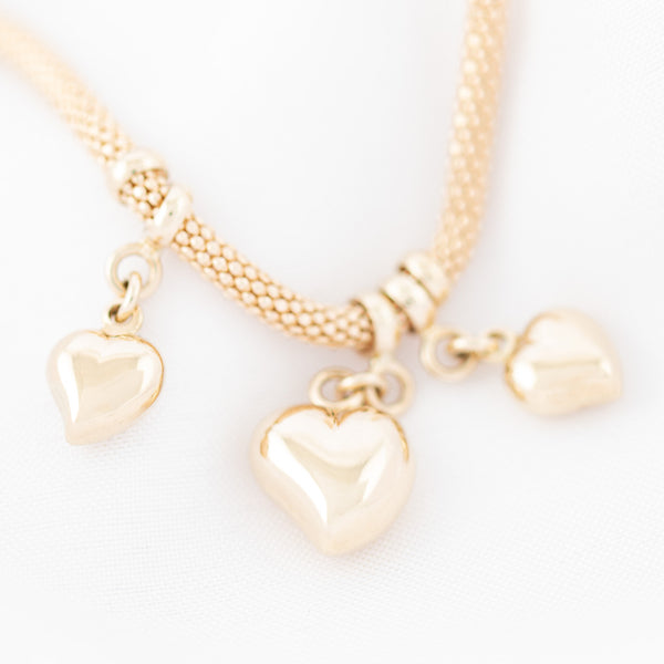 Pulsera eslabón tejido con colgantes motivo corazón en oro amarillo 14 kilates.