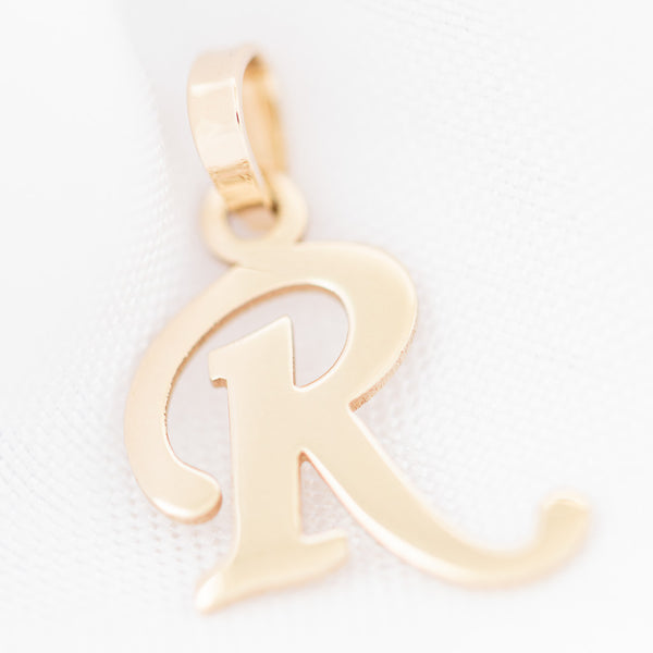 Dije liso motivo letra R en oro amarillo 14 kilates.