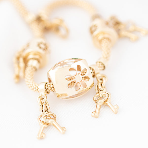 Pulsera eslabón tejido con aplicaciones y colgantes motivo llaves en oro amarillo 14 kilates.
