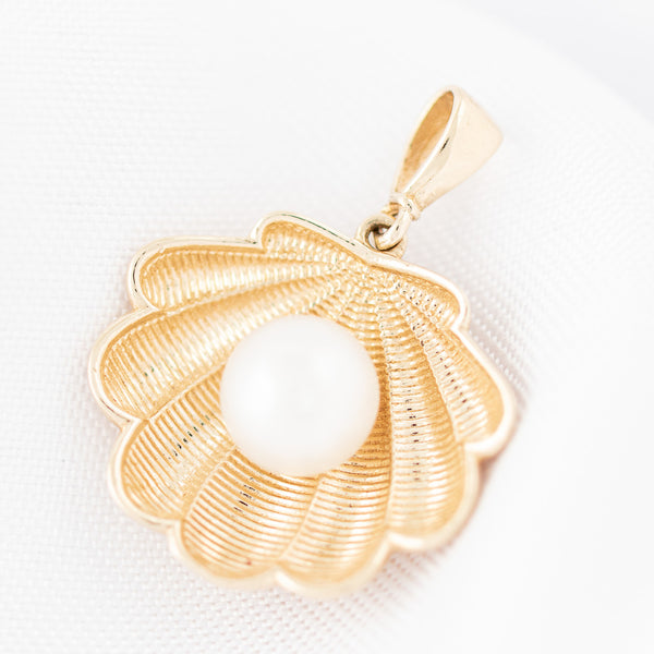 Dije diseño especial motivo concha con perla en oro amarillo 14 kilates.