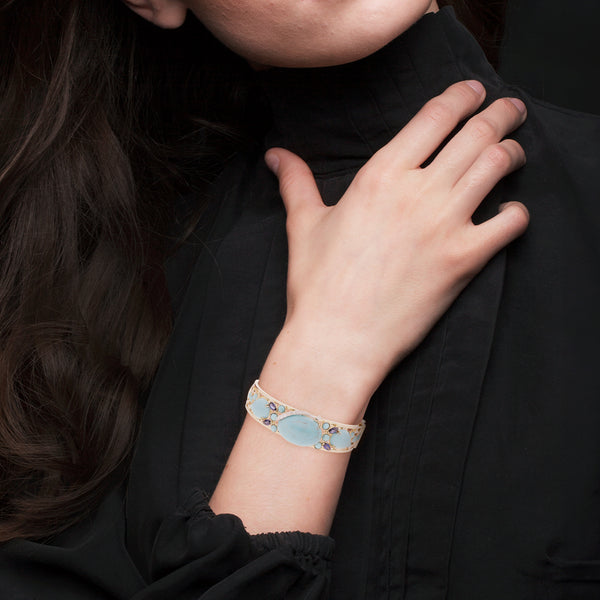 Pulsera de arillo calada con diamantes, zafiros y turquesas en oro amarillo 14 kilates.