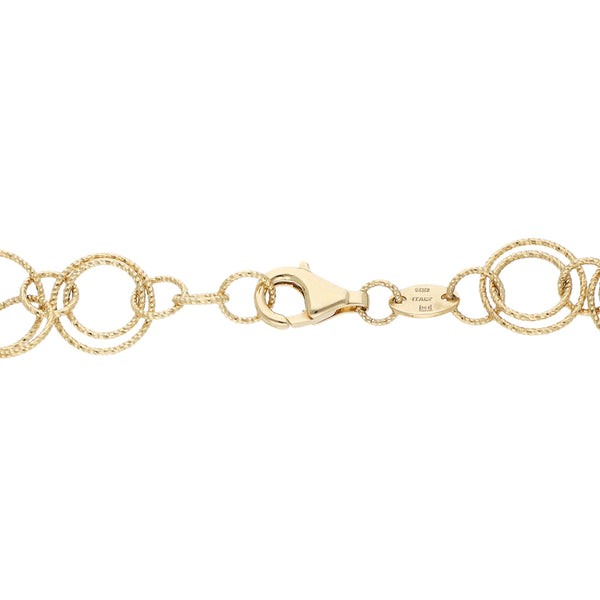 Pulsera eslabón cruzado con colgante motivo bolsa y sintéticos en oro amarillo 14 kilates.