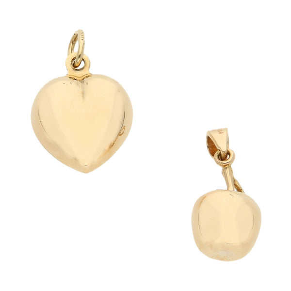 Dos dijes huecos motivo corazón y manzana en oro amarillo 14 kilates.