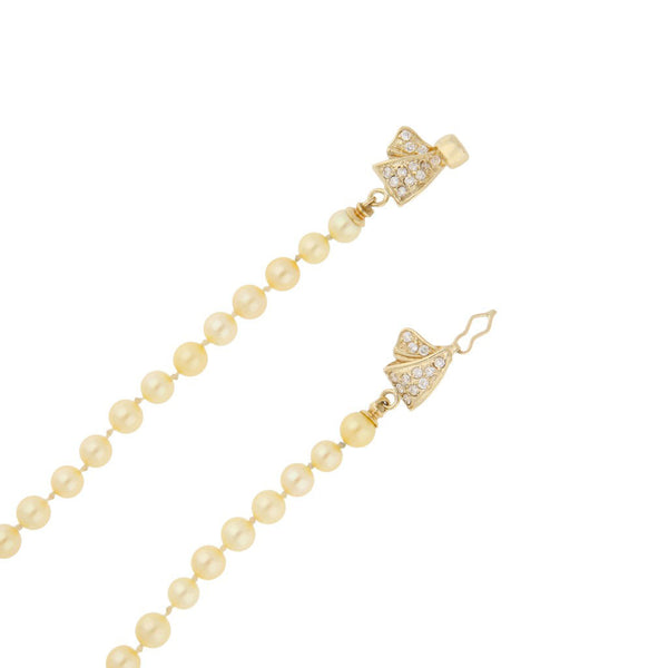 Collar de perlas diseño especial con broche aplicación motivo moño y sintéticos en oro amarillo 14 kilates.