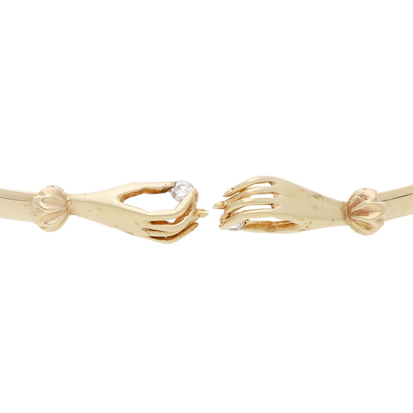Pulsera de arillo abierta con aplicaciones motivo manos y sintéticos en oro amarillo 14 kilates.