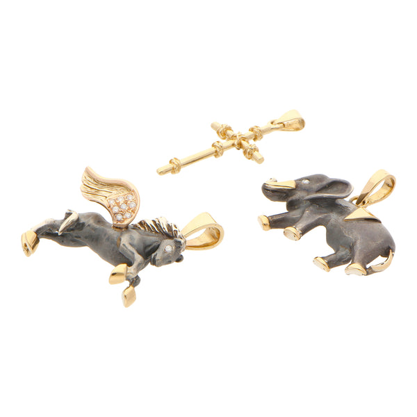 Juego de dos dijes motivo elefante y equino con sintéticos; cruz estilizada en plata y oro amarillo 14 kilates.
