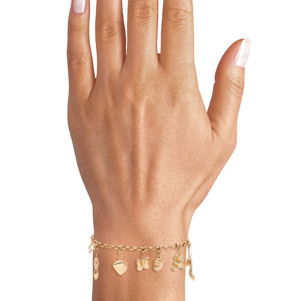 Pulsera eslabón cruzado con nueve dijes en oro amarillo 14 kilates.