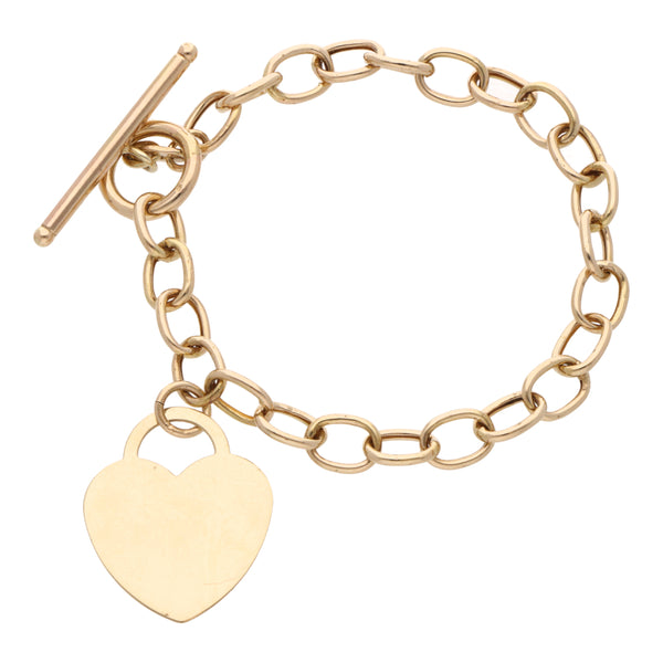 Pulsera eslabón cruzado con dije motivo corazón en oro amarillo 14 kilates.