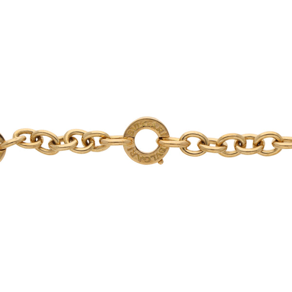 Pulsera eslabón cruzado firma Bvlgari con dijes, ónix y diamante en oro amarillo 18 kilates.