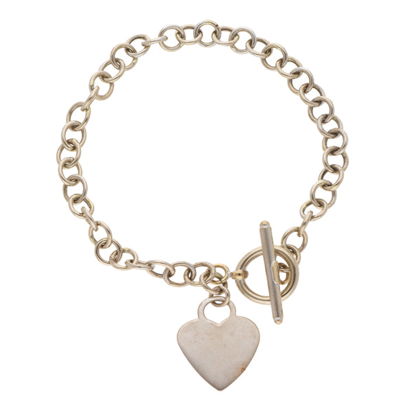 Pulsera eslabón cruzado con dije motivo corazón en oro blanco 14 kilates.