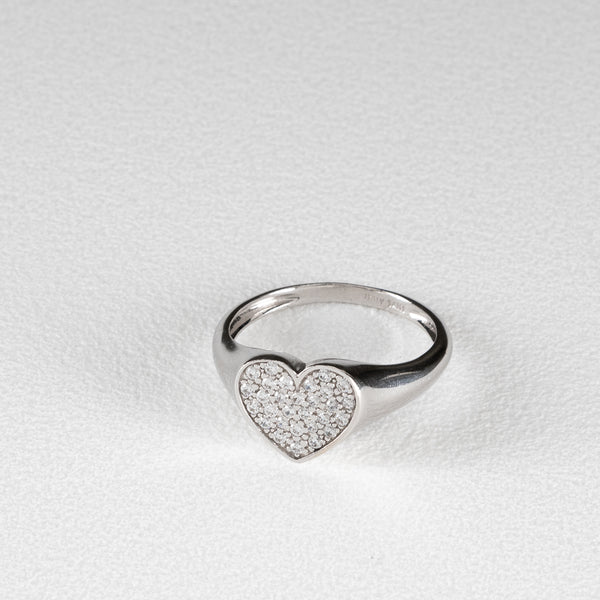 Anillo tipo sello motivo corazón con circonias en oro blanco 14 kilates.