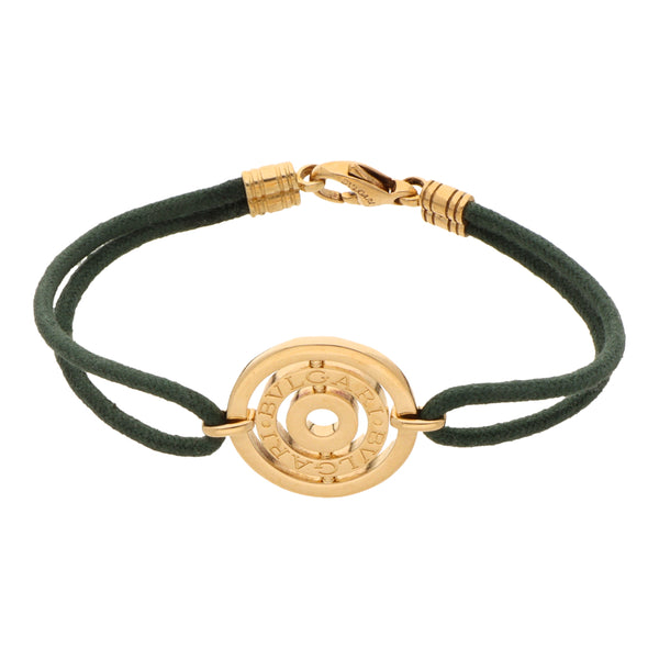 Pulsera diseño italiano firma Bvlgari con cordón textil, aplicación, casquillos y broche en oro amarillo 18 kilates.