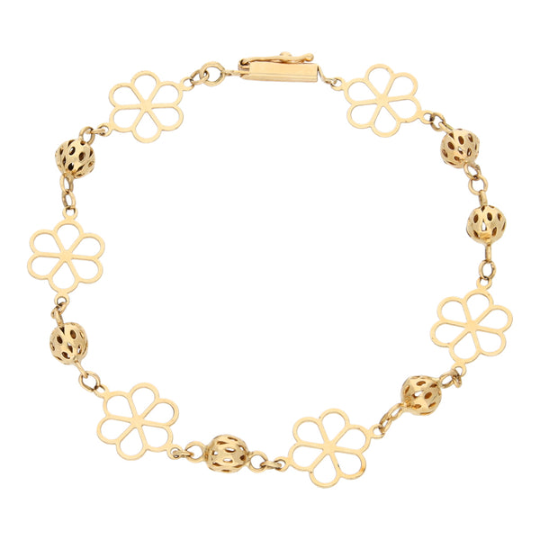 Pulsera eslabón cruzado con esferas caladas y aplicaciones motivo floral en oro amarillo 14 kilates.