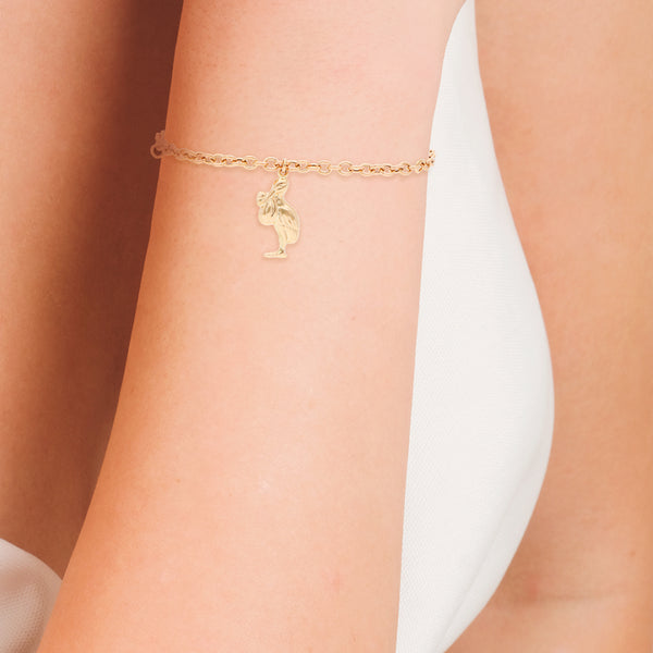 Pulsera eslabón cruzado con colgante motivo cigüeña en oro amarillo 14 kilates.