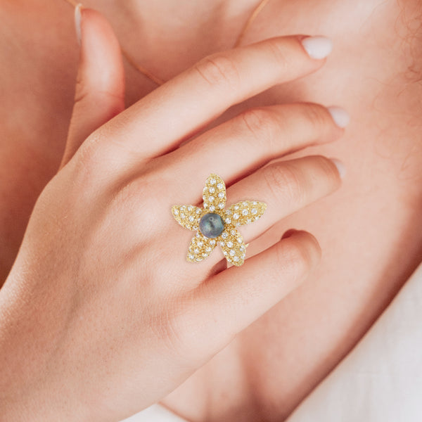 Anillo estilizado motivo estrella de mar con perla y circonias en oro amarillo 14 kilates.