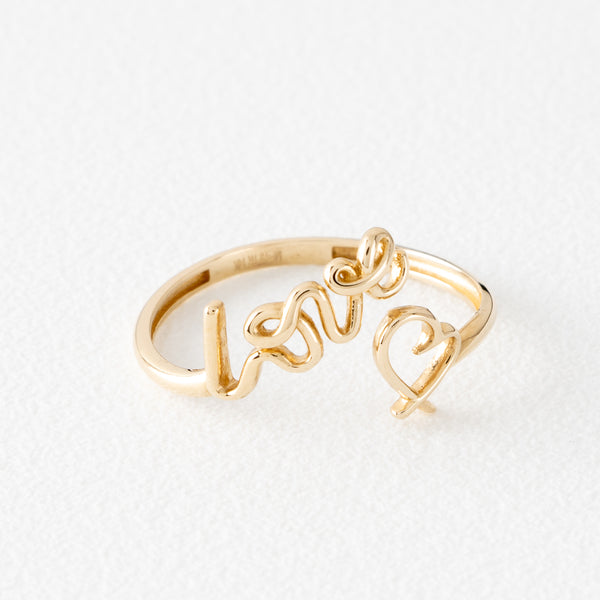 Anillo abierto motivo letras y corazón en oro amarillo 14 kilates.