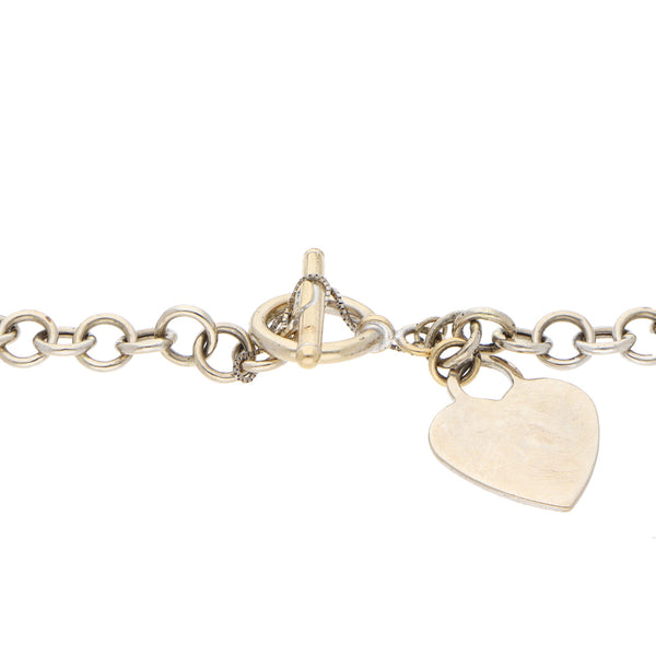 Pulsera eslabón cruzado con colgante motivo corazón en oro blanco 14 kilates.