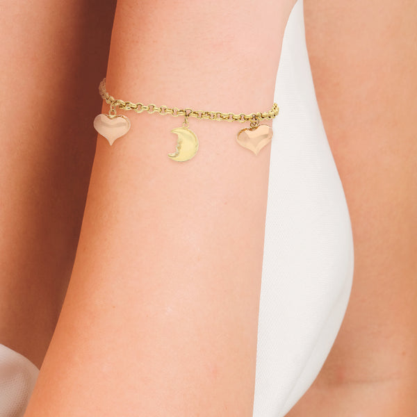 Pulsera eslabón cruzado con colgantes motivo estrella, luna y corazón en oro dos tonos 18 kilates.