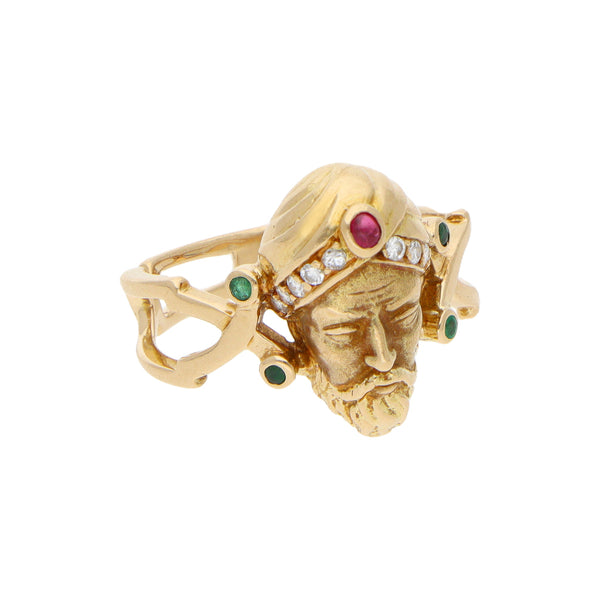 Anillo calado motivo rostro con diamantes, esmeraldas y rubí en oro amarillo 18 kilates.