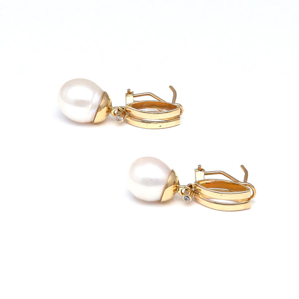 Aretes estilizados con perla calabazo y circonias en oro amarillo 14 kilates.