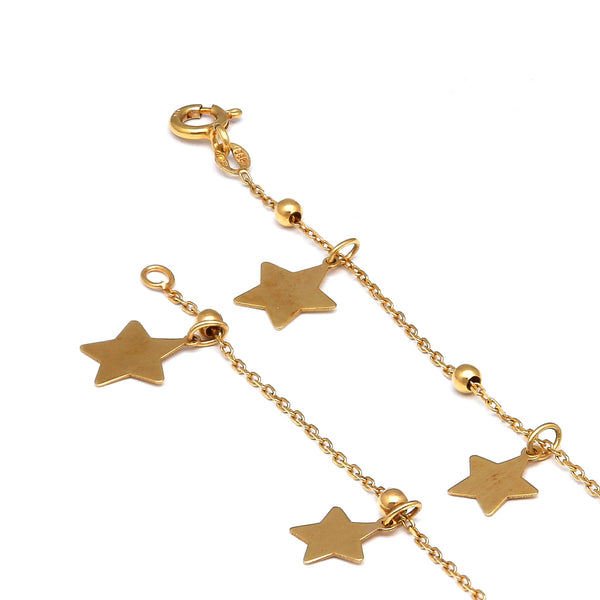 Pulsera eslabón cruzado con esferas y dijes motivo estrella en oro amarillo 14 kilates.