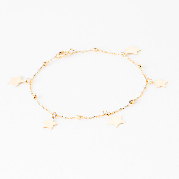 Pulsera eslabón cruzado con esferas y dijes motivo estrella en oro amarillo 14 kilates.