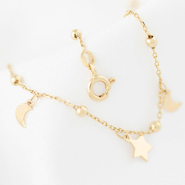 Pulsera eslabón cruzado con esferas y colgantes motivo lunas y estrellas en oro amarillo 14 kilates.