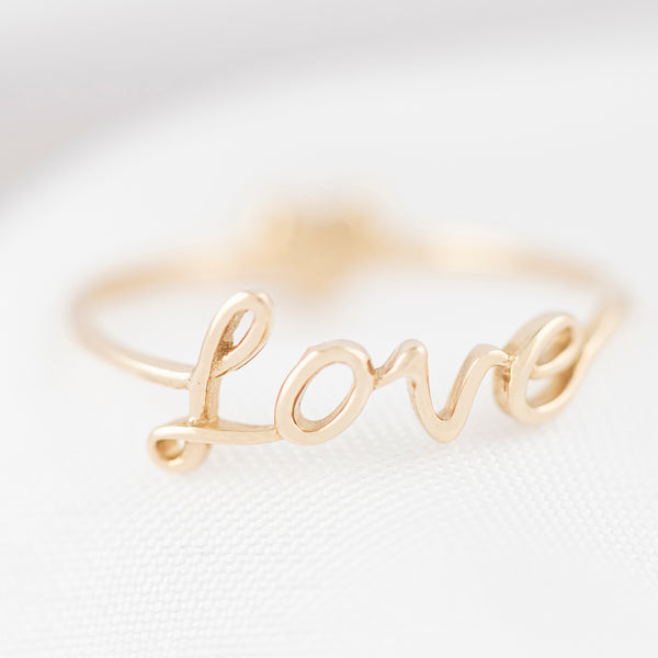 Anillo diseño especial motivo letras y corazón con circonias en oro amarillo 14 kilates.